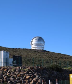A large observatory dome sits on a hill beneath a clear blue sky, ideal for astronomy enthusiasts.