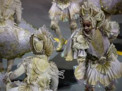 Bob Mackie Understood That Costume Was Part of the Performance Dazzling carnival performers in intricate white and gold costumes at a vibrant parade.