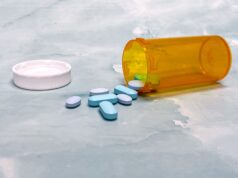 Medicaid Drug Prices May Fall. Patients Still Do Not Know Which Medicines Will Change Scattered blue pills and an orange prescription bottle on a light surface.