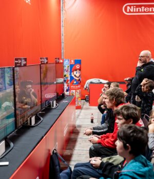pexels-photo-19228377-1 A lively group enjoys gaming at a Nintendo event in Zagreb, featuring multiple screens and vibrant atmosphere.