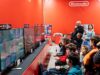 BlizzCon Sold Out, but Anaheim Is Carrying the Larger Economic Bet A lively group enjoys gaming at a Nintendo event in Zagreb, featuring multiple screens and vibrant atmosphere.