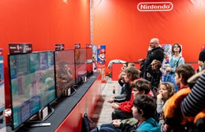 BlizzCon Sold Out, but Anaheim Is Carrying the Larger Economic Bet A lively group enjoys gaming at a Nintendo event in Zagreb, featuring multiple screens and vibrant atmosphere.