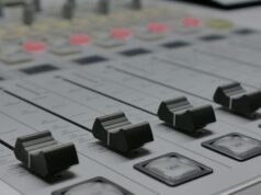 The Emergency Alert System Has a New Cybersecurity Rule. The Hard Part Is Knowing What It Touches. Detailed view of audio mixer sliders in a recording studio setting.