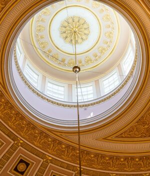 Captivating view of a domed ceiling with intricate golden patterns and sunlight from Washington, D.C.