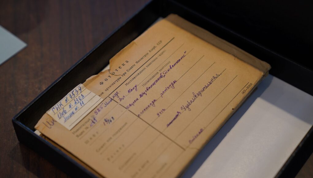 pexels-photo-33656448 An old Russian document placed inside an archive box on a wooden desk.