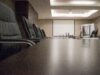 Berkshire Hathaway’s Buffett Succession Is Complete. The Harder Test Starts Now. Empty conference room with black chairs, projector, and glasses on table. Ideal for business meetings.