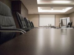 Berkshire Hathaway’s Buffett Succession Is Complete. The Harder Test Starts Now. Empty conference room with black chairs, projector, and glasses on table. Ideal for business meetings.
