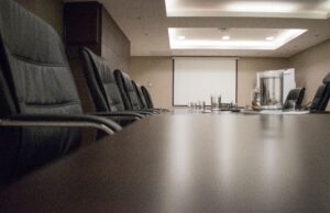Berkshire Hathaway’s Buffett Succession Is Complete. The Harder Test Starts Now. Empty conference room with black chairs, projector, and glasses on table. Ideal for business meetings.