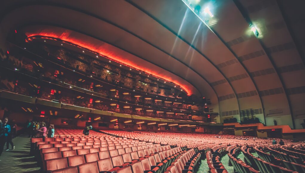 pexels-photo-5691279 Expansive interior of a modern theater with rows of empty seats and warm lighting creating an inviting atmosphere.