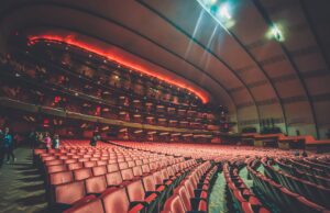 Broadway Has Become a Certification System for New Ideas Expansive interior of a modern theater with rows of empty seats and warm lighting creating an inviting atmosphere.