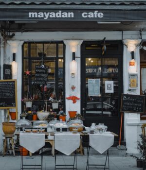 pexels-photo-7385395 An inviting outdoor café showcasing local food, menu boards, and charming decorations in a quaint neighborhood setting.