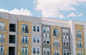Louisville Built Housing First. Now Its Federal Application Enters a New Test Contemporary apartment building exterior with yellow and grey panels under a clear blue sky.