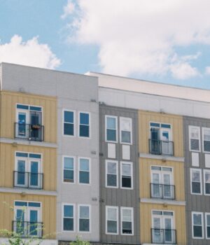 Contemporary apartment building exterior with yellow and grey panels under a clear blue sky.
