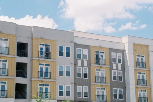 Louisville Built Housing First. Now Its Federal Application Enters a New Test Contemporary apartment building exterior with yellow and grey panels under a clear blue sky.
