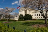pexels-photo-16151491 A view of a neoclassical government building with an American flag and cherry blossoms in Washington, DC.