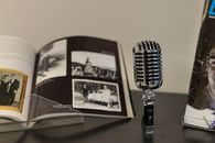The Smithsonian Has Collected Good Mythical Morning. Now It Has to Preserve the Internet. A classic vintage microphone beside an open photo album, nostalgic ambiance.