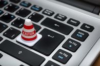 Chrome’s HTTPS Warning Is a Useful Security Upgrade. It Is Not a Trust Machine. Miniature caution cone on a computer keyboard symbolizing data security and control.