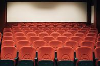 A Movie Theater Is an Architecture of Attention A spacious theater with empty red seats and a large screen, ready for the next audience.