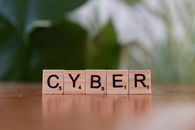 The Ad Wasn’t the Whole Attack. The Advertising Network Was. Wooden letter tiles spelling 'CYBER' on a blurred background, representing cybersecurity.