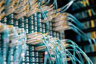 The FBI Seized the Tools. The Attack Pipeline Is Still the Problem From below of long thin blue cables connected to row of small white connectors on system block in data center
