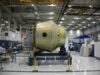 NASA Wants to Choose Science Missions Faster. The Risk Is Choosing Before the Engineering Is Ready Heavy detail of spacecraft placed on rolling platform under construction at futuristic rocket factory