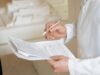 The Medicaid Frailty Ruling Shows Who Pays for Changing the Rules A doctor holds and reviews medical documents, demonstrating careful examination and professionalism.