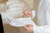 The Medicaid Frailty Ruling Shows Who Pays for Changing the Rules A doctor holds and reviews medical documents, demonstrating careful examination and professionalism.