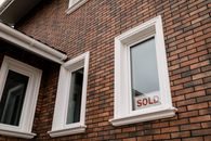 Builders Are Cutting Prices. Buyers Still Can’t Afford the House. Close-up of a brick house with a 'Sold' sign in the window, showcasing real estate sales.