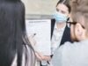 When School Health Insurance Gets More Expensive, Families and Classrooms Pay A professional woman explains a home insurance policy to clients during a meeting. Indoors setting.