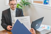 Small-Business Credit Is Available—Just Not on Equal Terms Mortgage broker and client discussing loan application with documents on table.