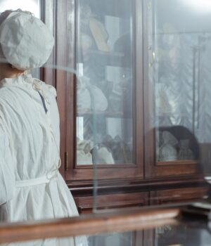 pexels-photo-8666840 A woman in vintage attire retrieves items from a pharmacy cabinet.